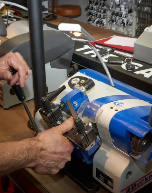 Slotenmaker-Rotterdam-sleutel-aan-het-bijmaken Slotenmaker maakt een autosleutel met een sleutelmachine bij Lockit.